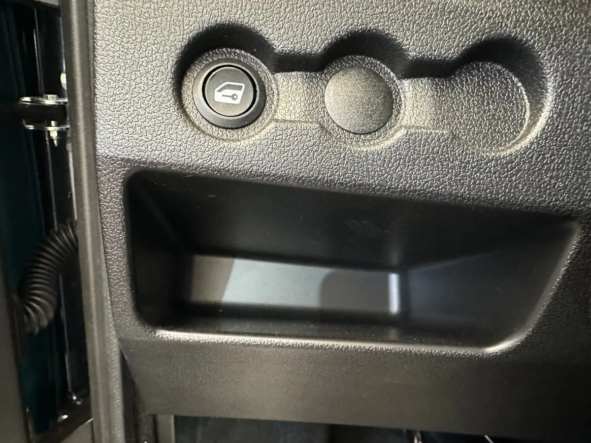 Gros plan sur le bouton d'ouverture du coffre côté conducteur de l'AIXAM AMBITION 0.5 CITY PACK bleu 2026.