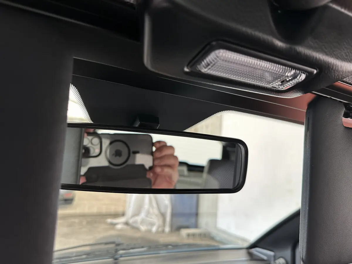 Vue intérieure centrée sur le rétroviseur intérieur de l'AIXAM Ambition 0.5 City Pack 2026, avec reflet du conducteur.