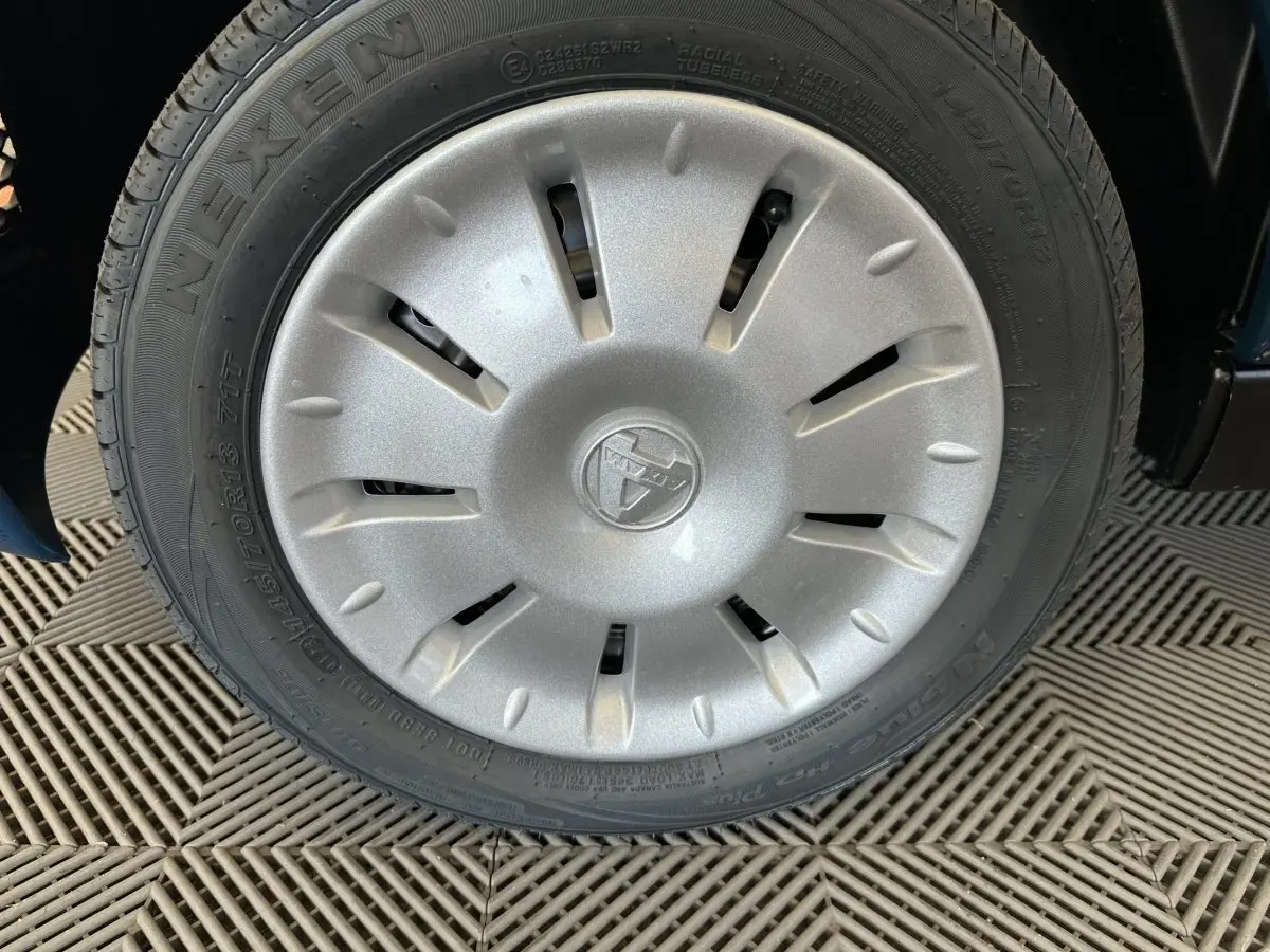 Gros plan sur la roue avant droite de l'AIXAM AMBITION 0.5 CITY PACK bleu, avec enjoliveur argenté et logo central.