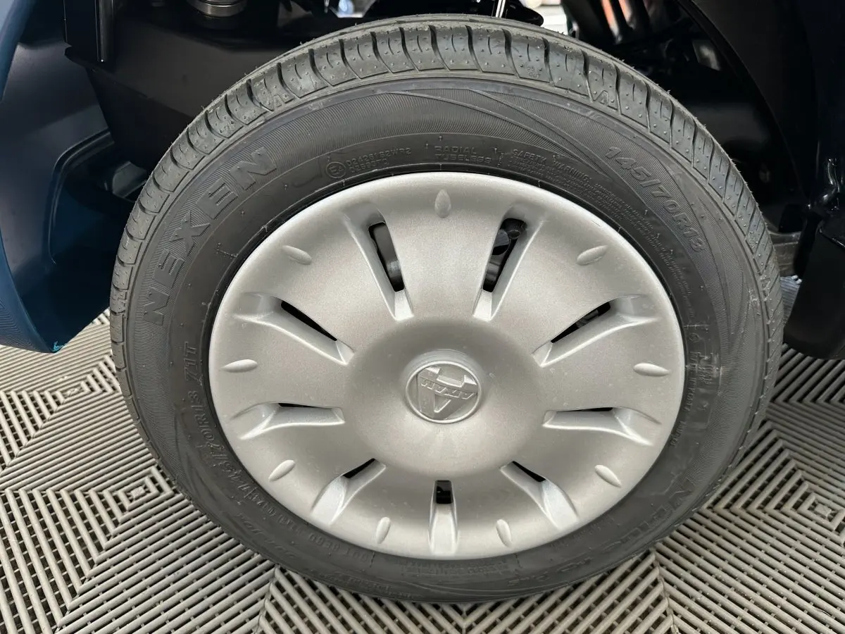 Gros plan sur la roue avant droite de l'AIXAM AMBITION 0.5 CITY PACK bleu, avec jante argentée et logo central.