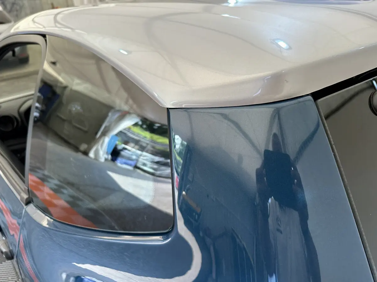 Vue rapprochée du côté arrière gauche de l’AIXAM Ambition bleu 2026 avec toit beige et vitre latérale teintée.