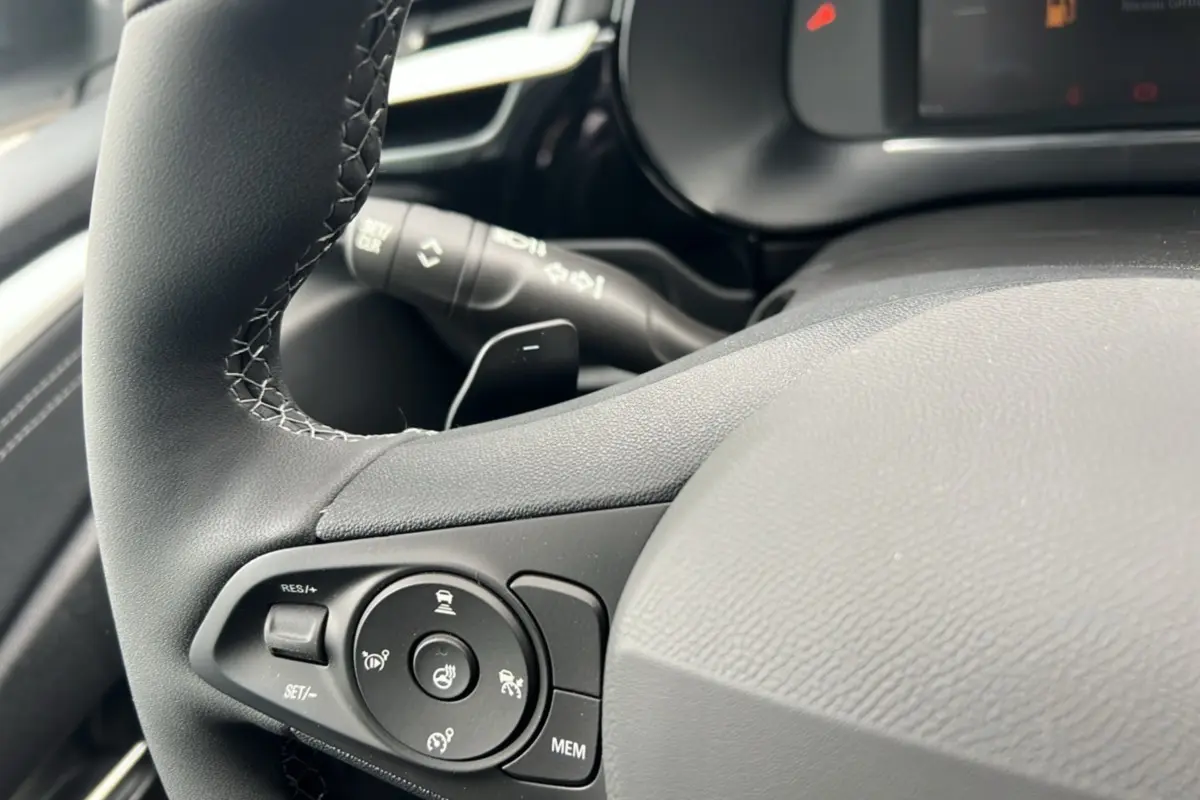 Gros plan sur le volant cuir noir de l’Opel Corsa Hybrid 2026 avec commandes multifonctions et bouton de chauffage.