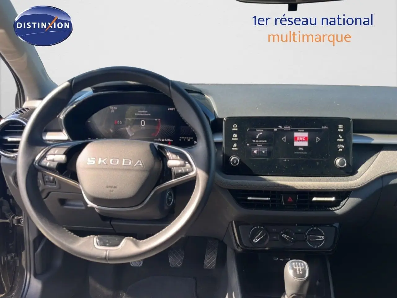 Vue intérieure centrée sur le volant SKODA et le tableau de bord avec écran tactile, ambiance sobre en noir.