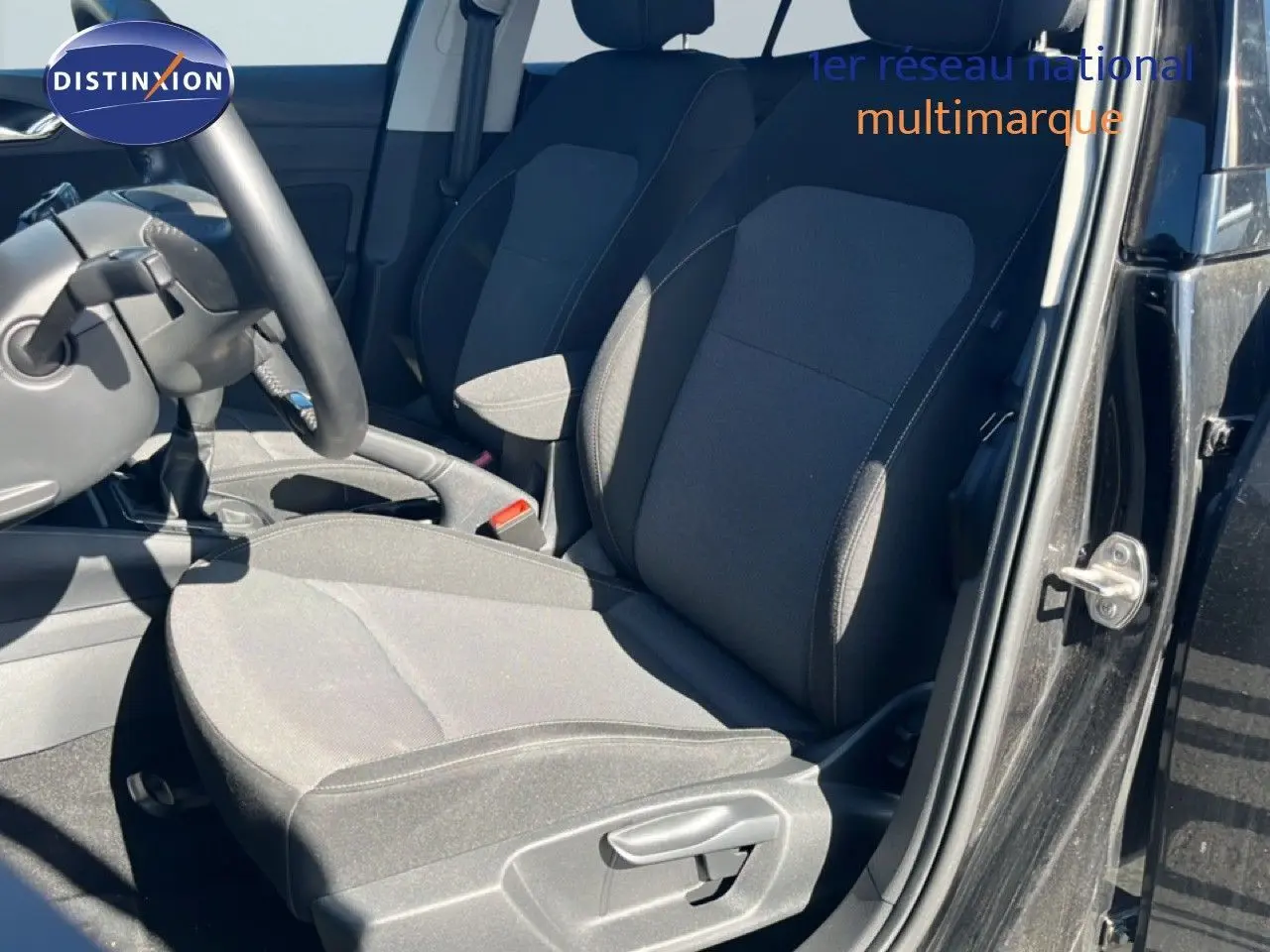 Vue intérieure côté conducteur de la Skoda Fabia 2025 noir magique métal, sièges tissu gris foncé et volant multifonctions.