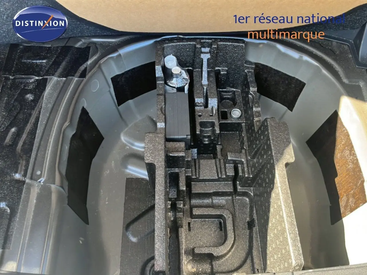 Vue en plongée sur le compartiment de roue de secours d'une Skoda Fabia 2025 noir magique métal, avec outils de bord rangés.