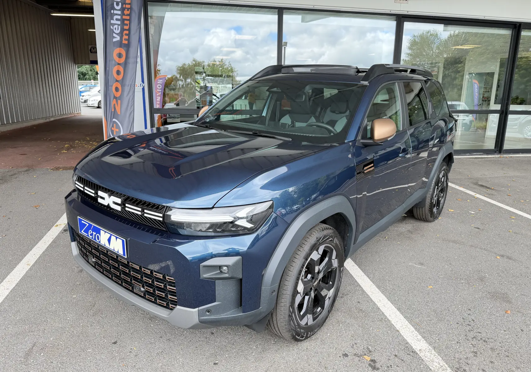 Vue 3/4 avant droite du Dacia Bigster Hybrid 155 Extreme bleu indigo avec jantes alliage noires et rétroviseurs bronze.