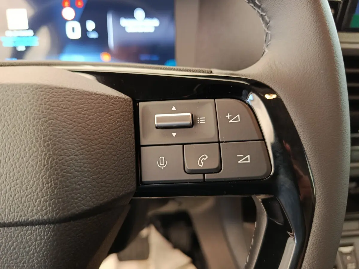 Gros plan sur les commandes multifonctions côté droit du volant du Peugeot Expert Fourgon XL noir, tableau de bord en arrière-plan flou.