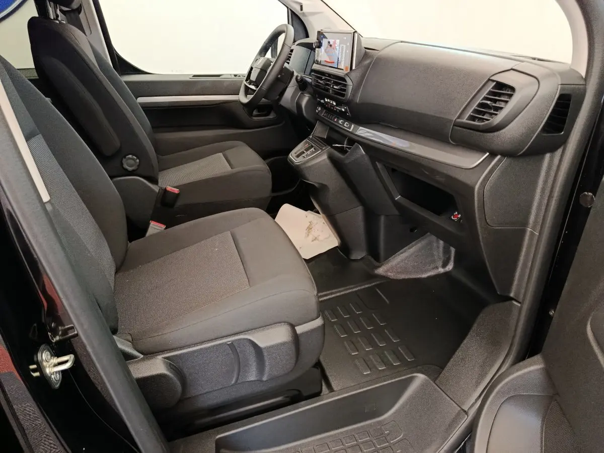 Vue intérieure côté passager avant du Peugeot Expert Fourgon noir, montrant les sièges et le tableau de bord moderne avec écran tactile.