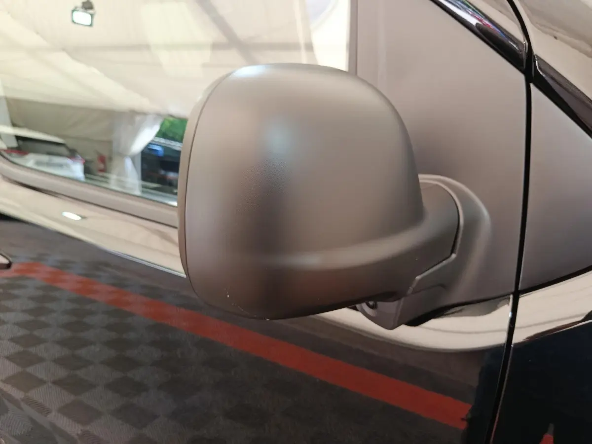 Gros plan sur le rétroviseur côté conducteur du Peugeot Expert Fourgon XL noir, avec reflet de l'environnement intérieur.
