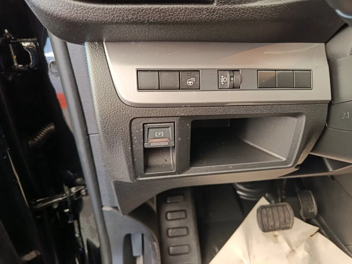Détail intérieur côté gauche du Peugeot Expert Fourgon noir, montrant les commandes de frein à main électrique et réglage des phares.
