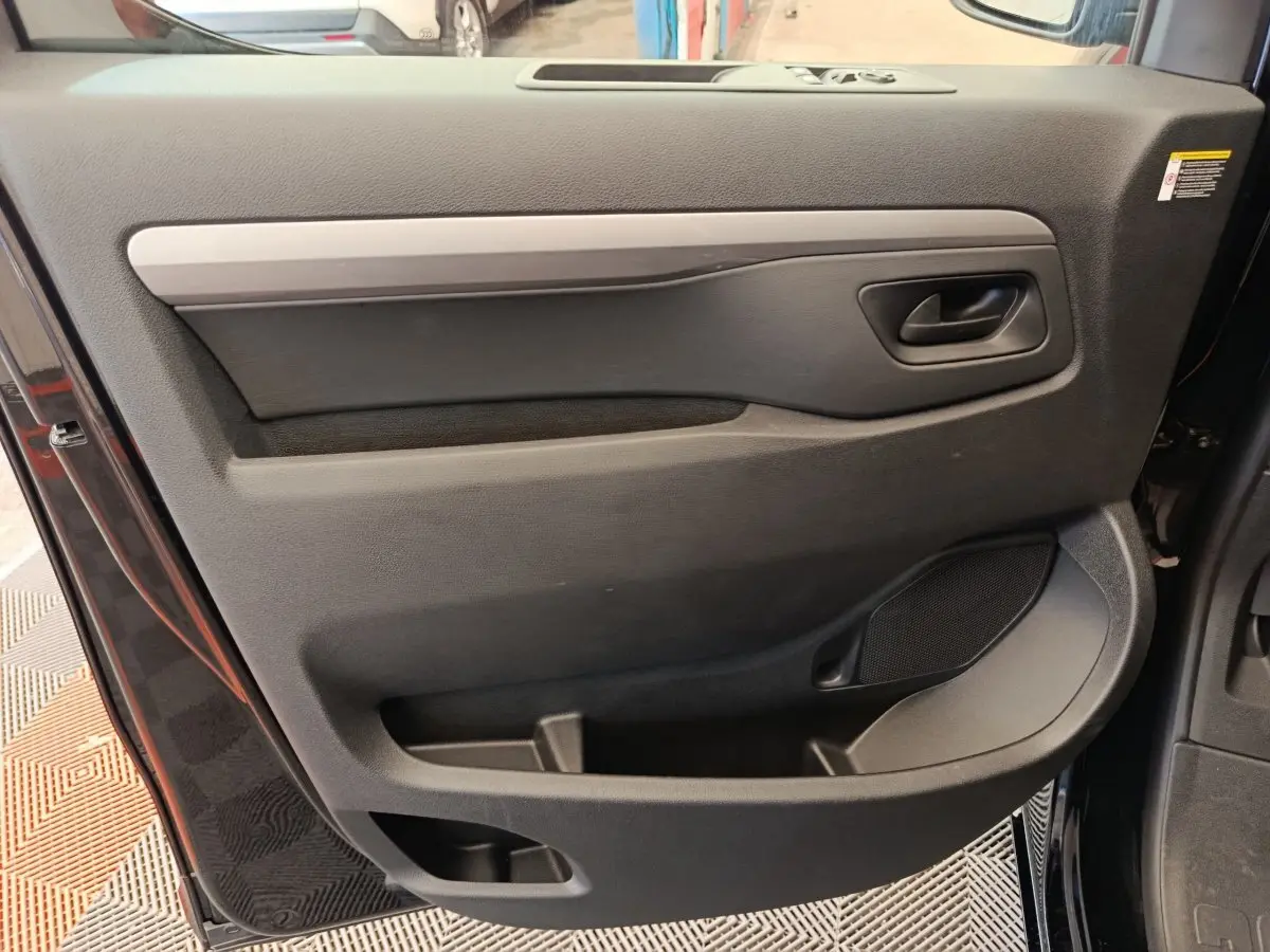 Vue intérieure de la porte avant droite noire du Peugeot Expert Fourgon XL Diesel 2026 avec poignée et rangements intégrés.