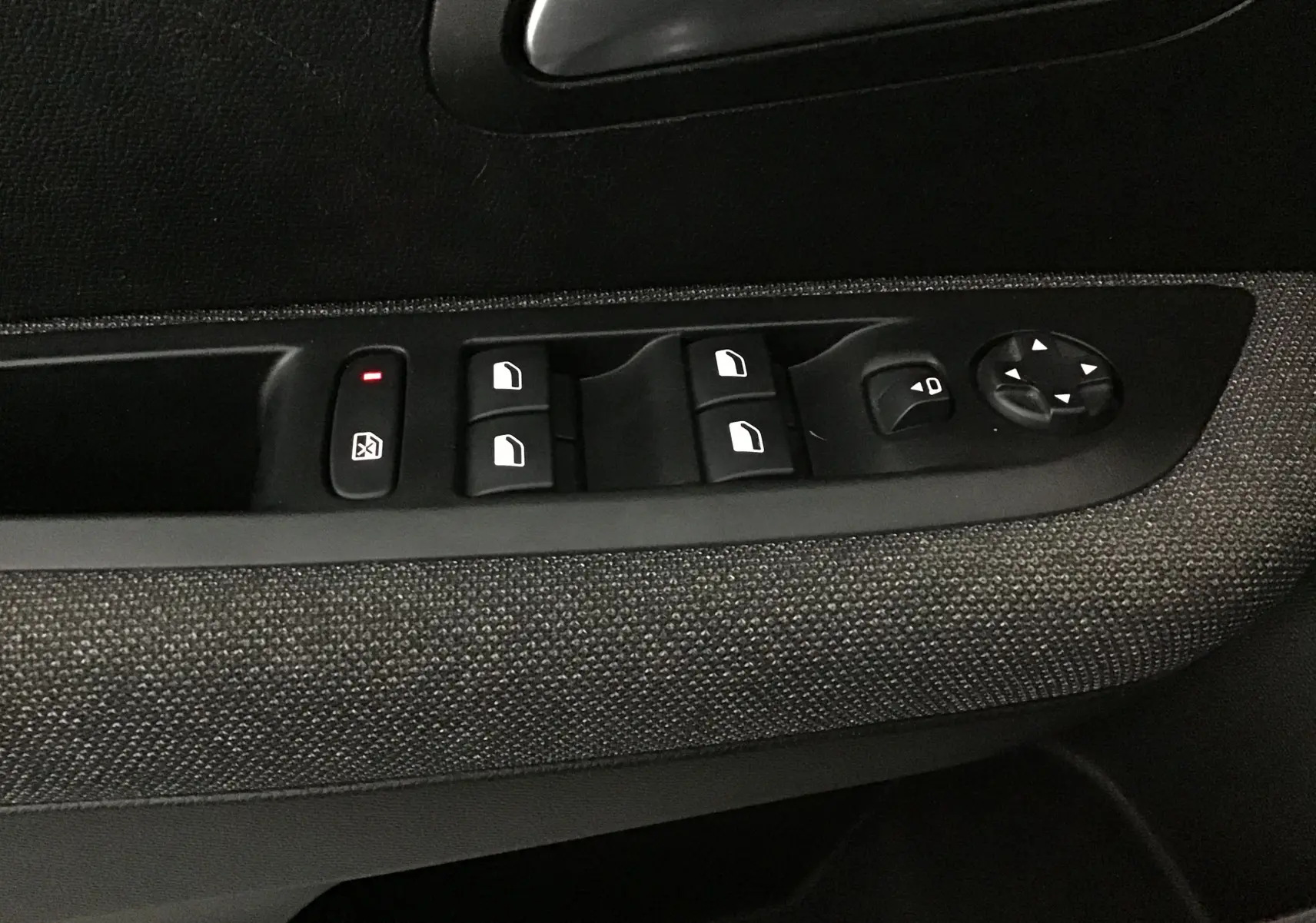 Panneau de commandes des vitres et rétroviseurs côté conducteur d'une Peugeot 208 noire, tissu gris.