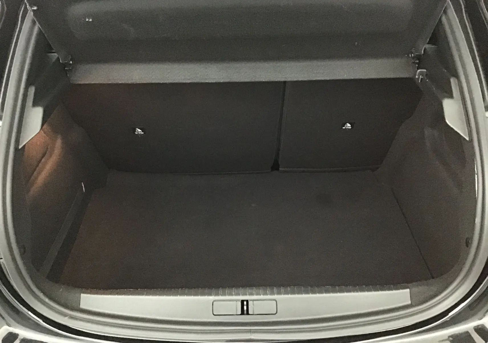Coffre ouvert d'une Peugeot 208 noire, vue de dessus montrant un espace de chargement vide et propre.