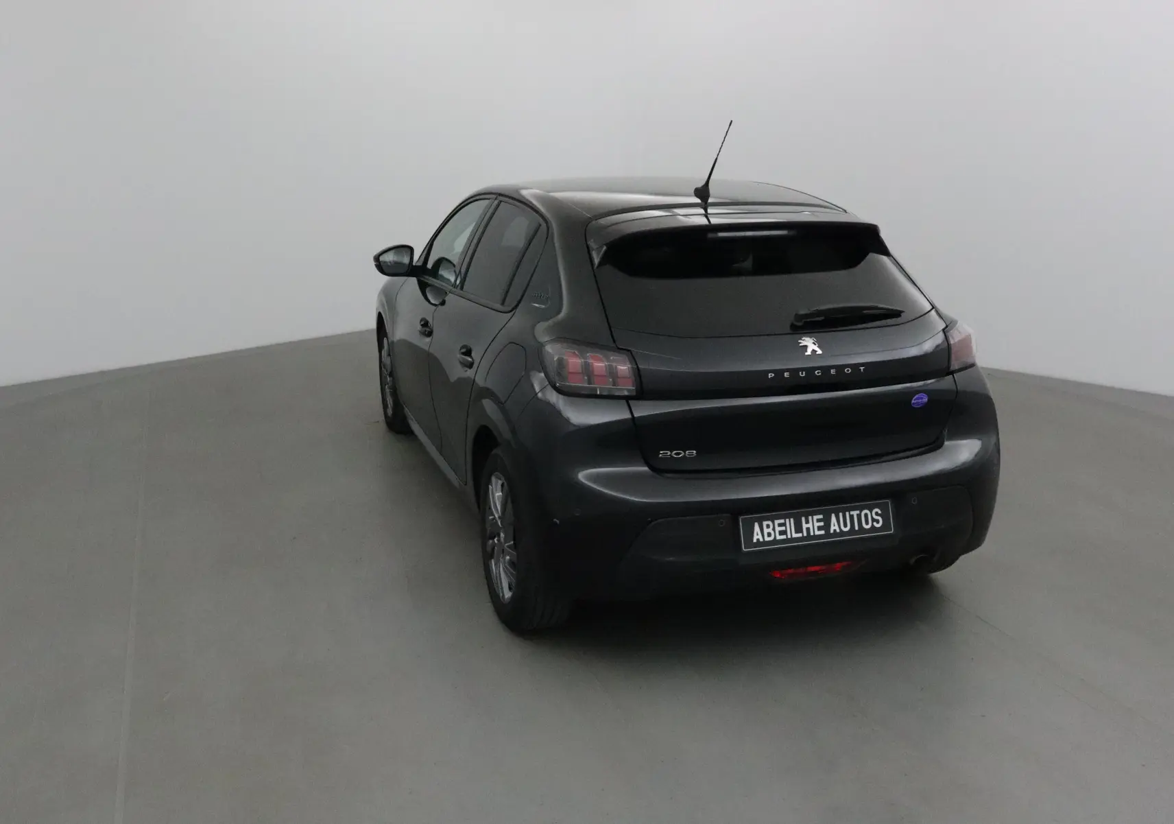 Vue 3/4 arrière d'une Peugeot 208 noire 2022 avec feux arrière distinctifs et antenne de toit visible.