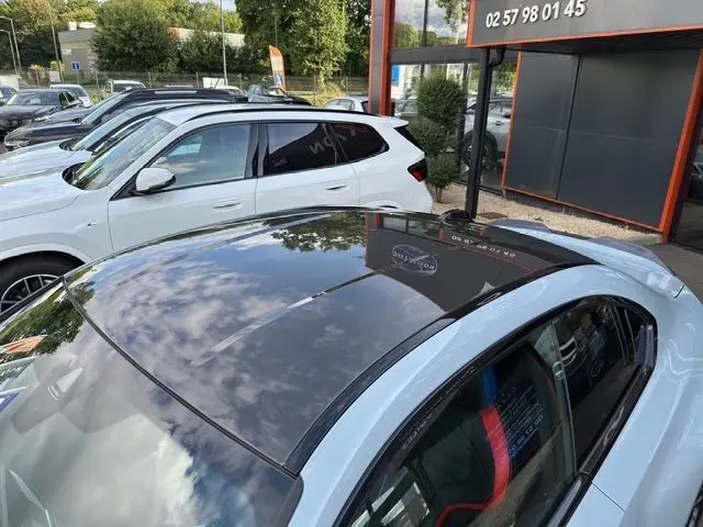 Vue plongeante sur le toit en carbone noir brillant d'une BMW M2 G87 gris Brooklyn Grau avec intérieur sport visible.