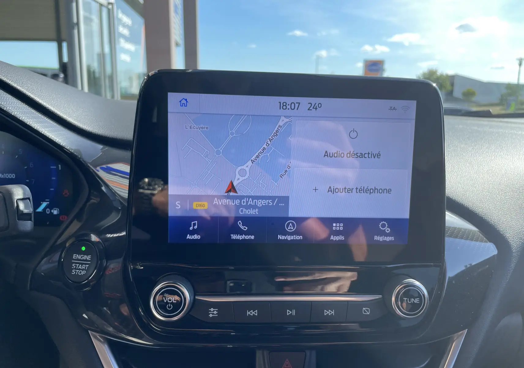 Vue rapprochée de l'écran tactile central du Ford Puma 1.0I 125 MHEV rouge, affichant la navigation et commandes audio.