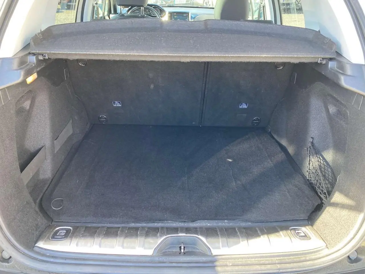 Coffre ouvert de la Peugeot 2008 2019, vue arrière, montrant un espace de chargement noir avec cache-bagages en place.