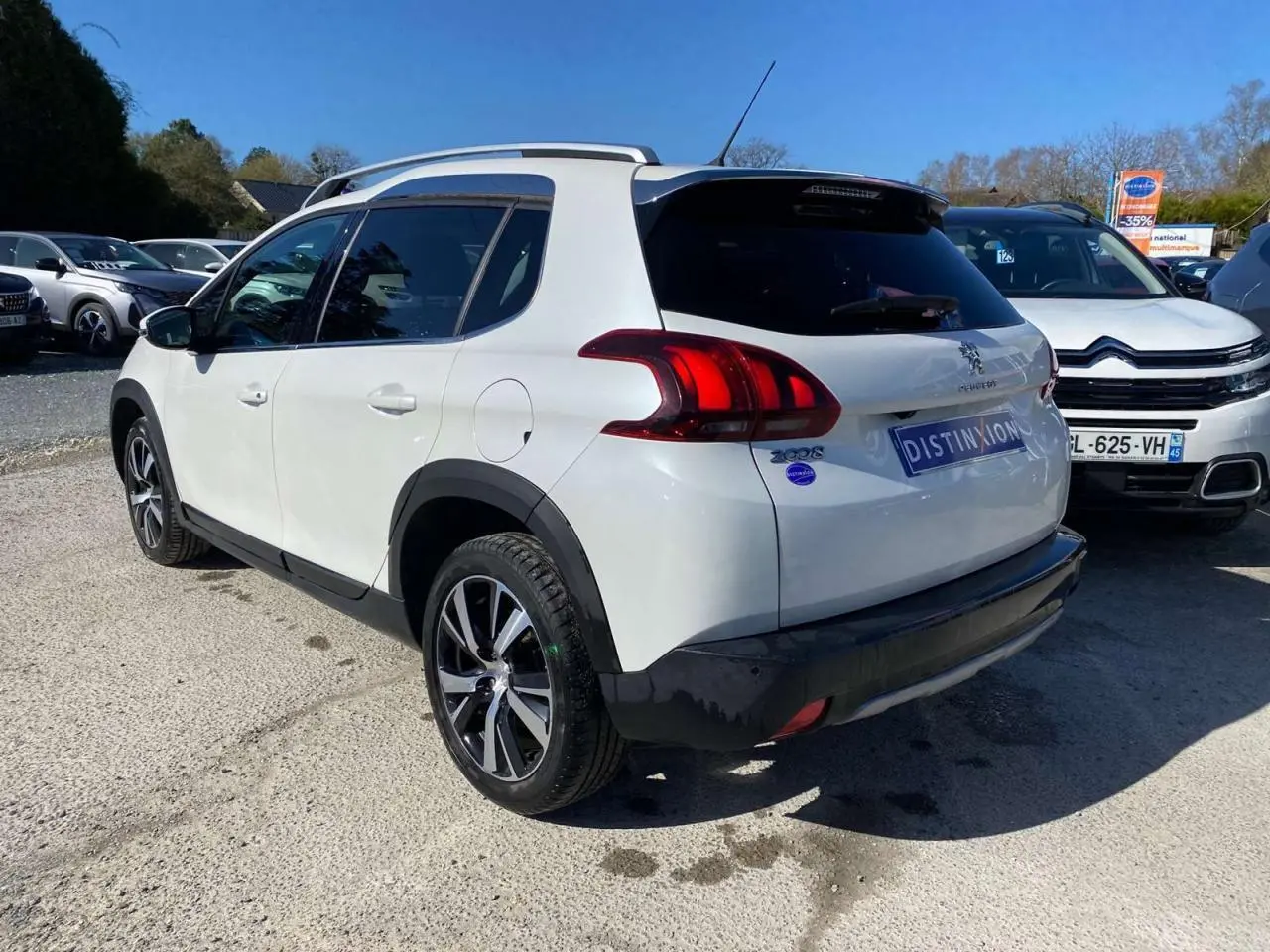 Vue 3/4 arrière droite d'un Peugeot 2008 blanc avec jantes alliage 17'' et vitres arrière surteintées.