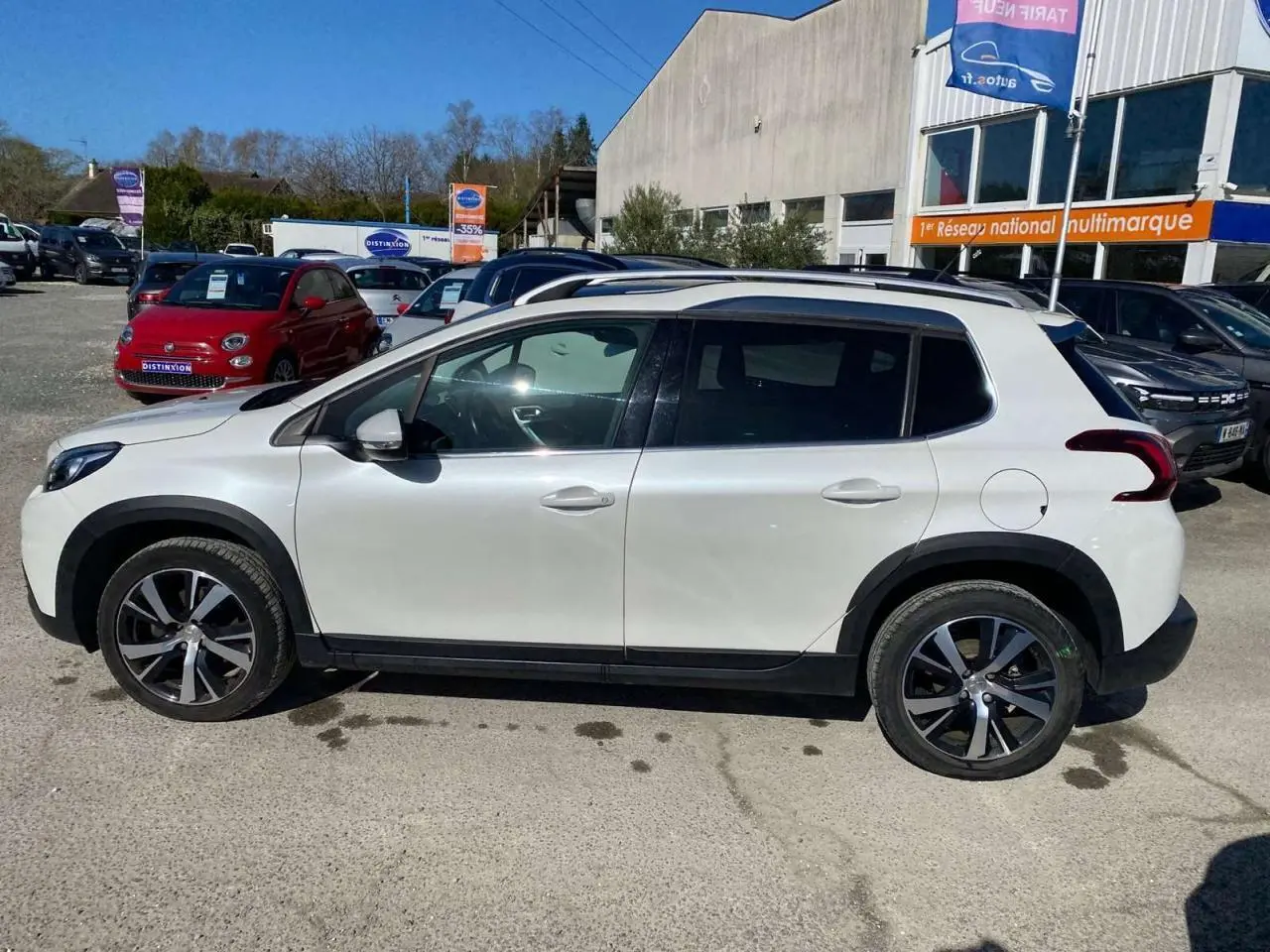 Peugeot 2008 essence 2019 vue de profil côté gauche, carrosserie blanche et jantes aluminium 17 pouces.