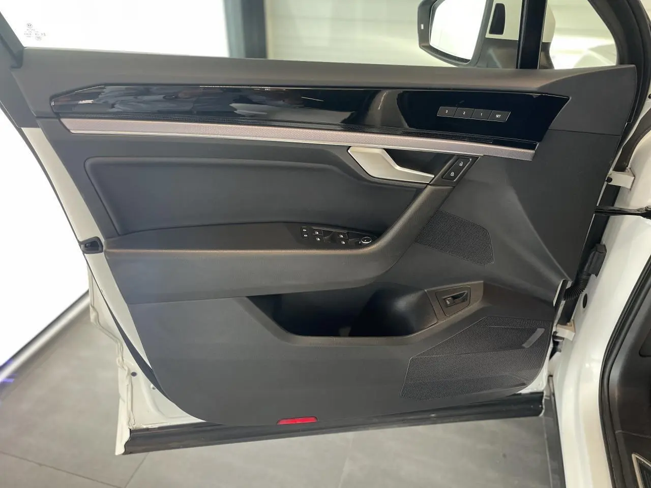 Vue intérieure de la porte avant gauche du Volkswagen Touareg blanc, avec garniture noire et inserts laqués piano.