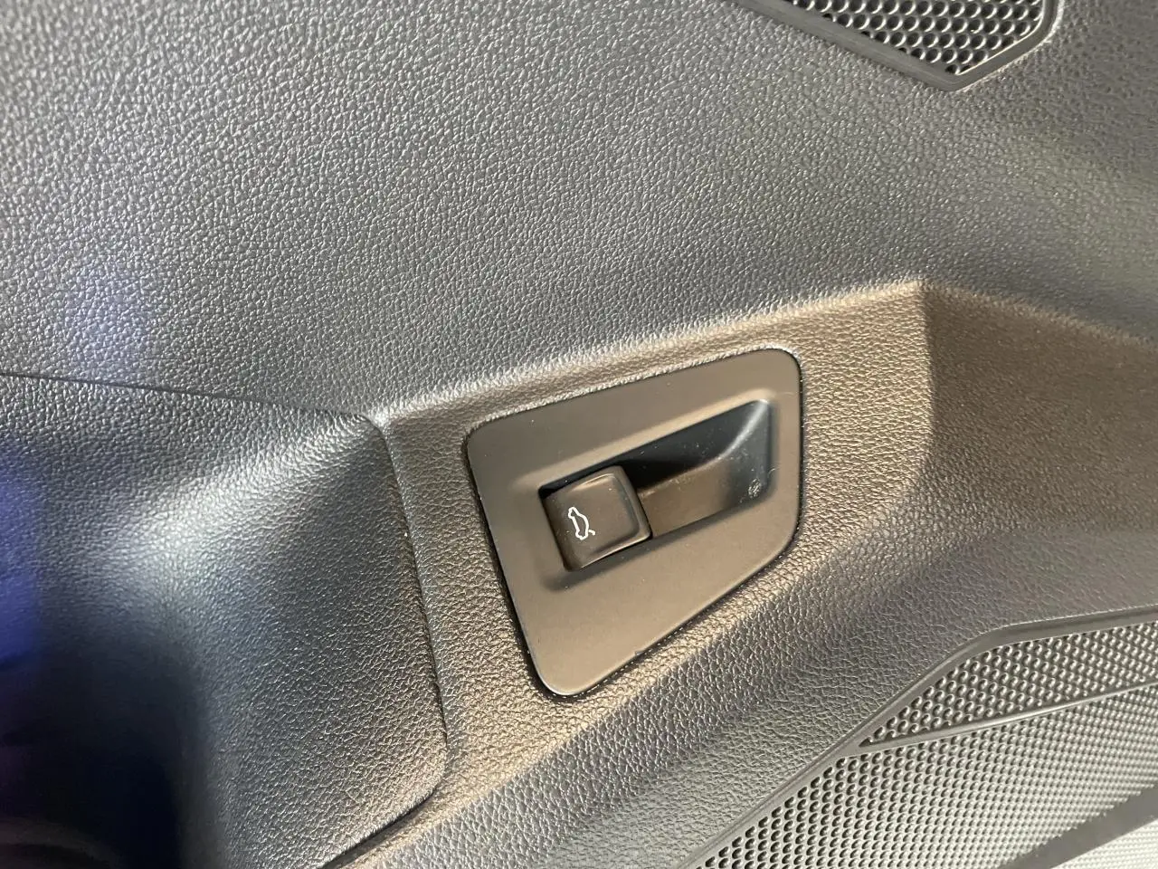 Bouton d'ouverture du hayon sur panneau intérieur noir texturé d'un Volkswagen Touareg blanc 2019.