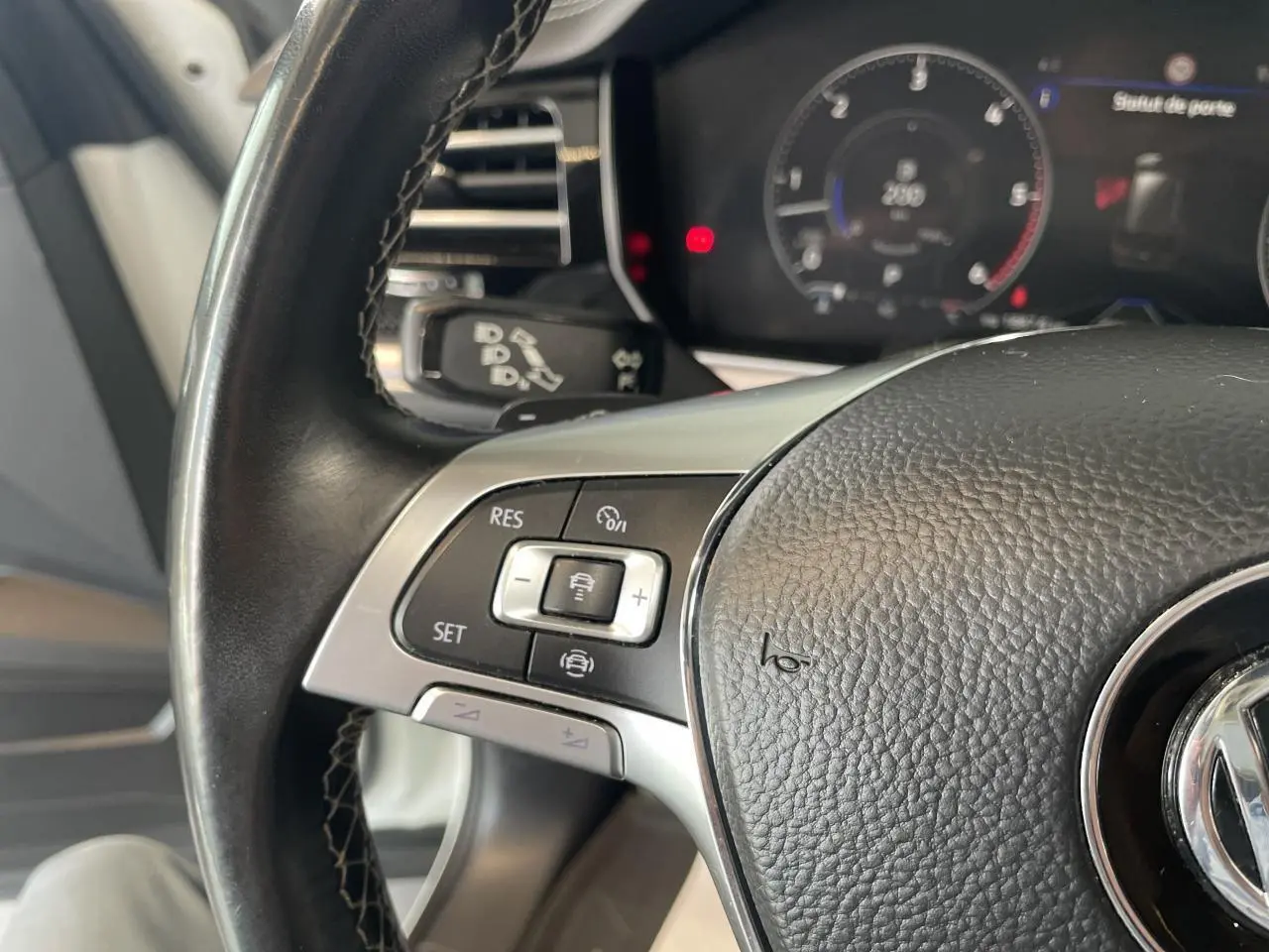 Gros plan sur le volant cuir noir multifonction R-Line du Volkswagen Touareg blanc, avec commandes de régulateur adaptatif visibles.