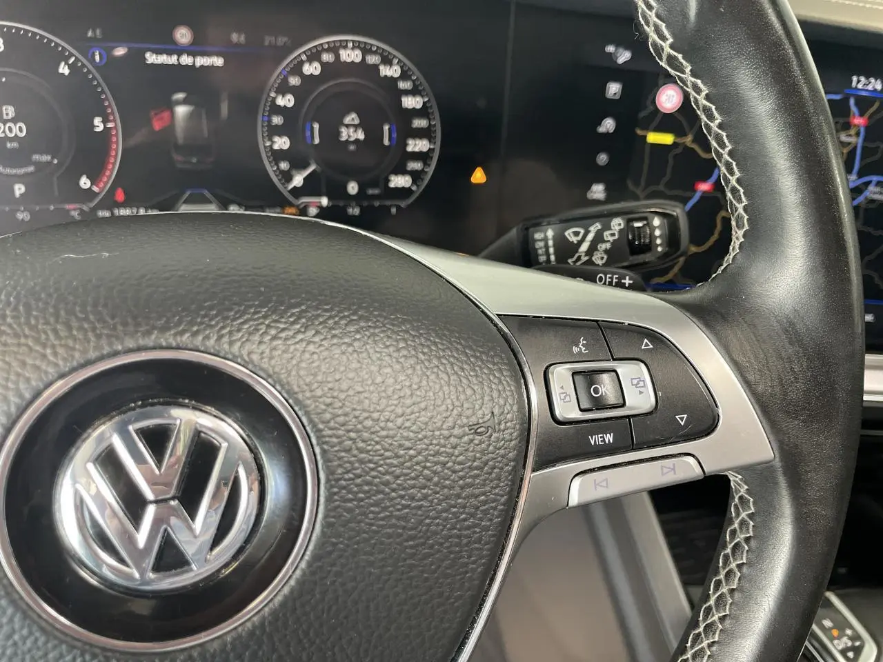 Gros plan sur le volant cuir noir R-Line avec commandes multifonctions et tableau de bord numérique du Volkswagen Touareg blanc.