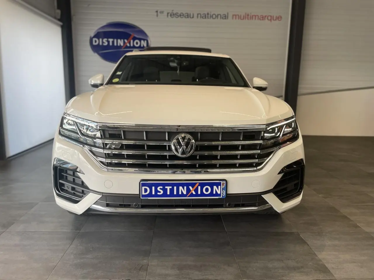 Vue frontale d'un Volkswagen Touareg blanc 2019 avec calandre chromée et logo R-Line visible sur le grillage.