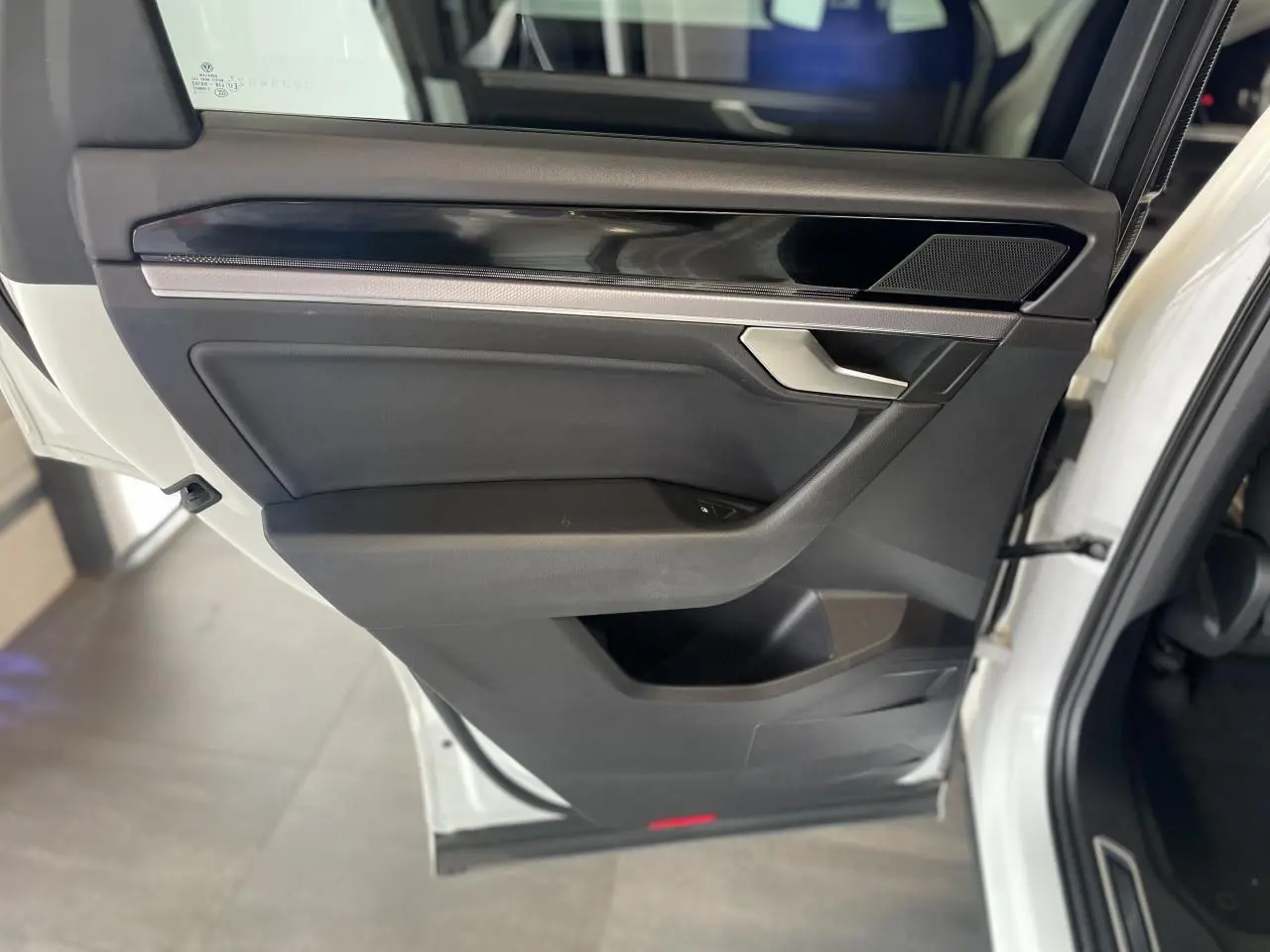 Porte avant droite ouverte d'un Volkswagen Touareg blanc, avec garniture noire et insert laqué piano.