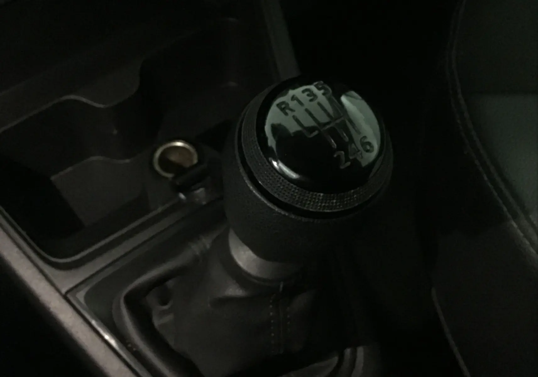 Gros plan sur le levier de vitesses manuel noir du Renault Express Van 2023, intérieur sombre et console centrale visible.