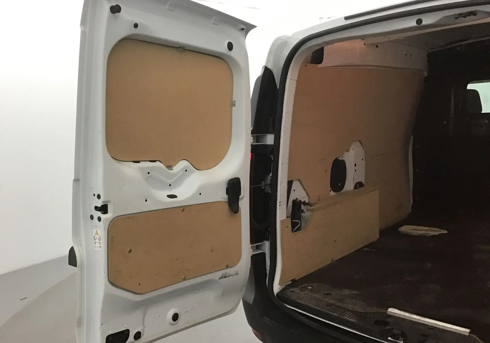Vue arrière ouverte du Renault Express Van blanc 2023, montrant l'intérieur utilitaire avec panneaux de protection en bois.