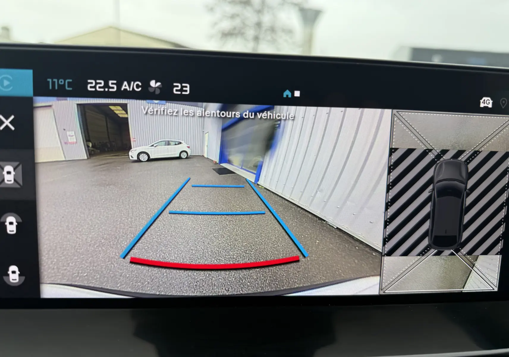 Vue caméra de recul d'une Citroën C4 Hybrid 145 blanc Okenite, avec lignes de guidage bleues et rouges visibles.