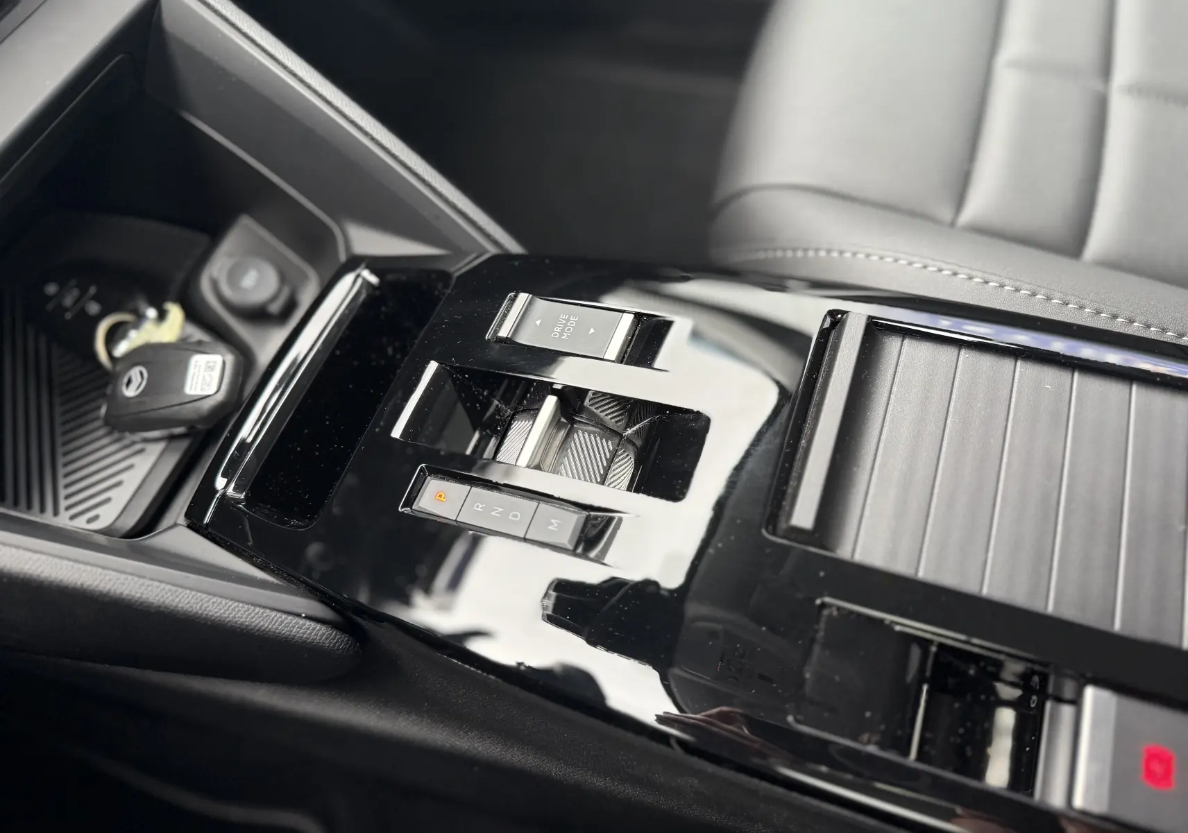 Vue rapprochée de la console centrale noire brillante avec sélecteur de boîte auto et clé dans une Citroën C4 Hybrid 145 blanche.