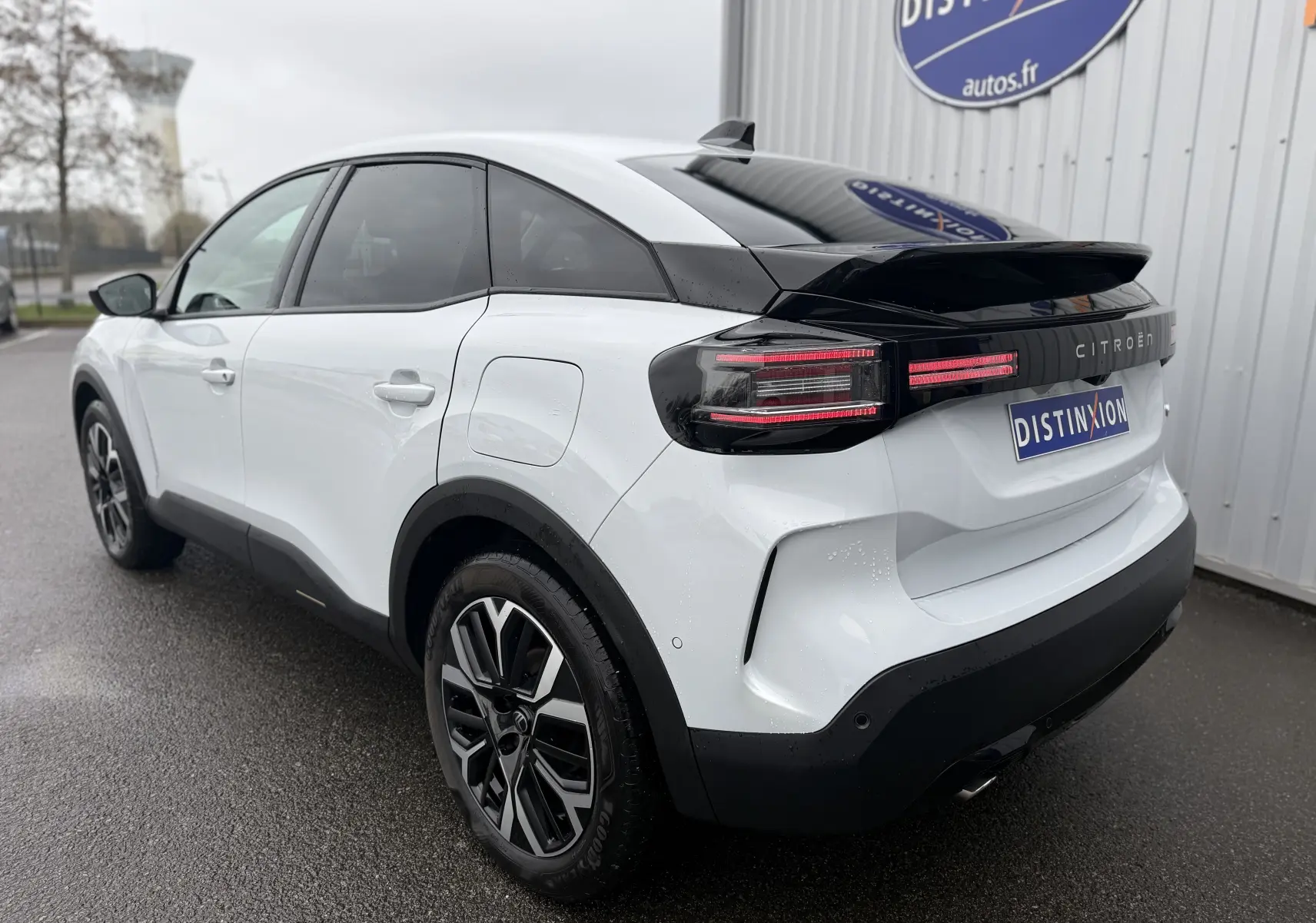 Vue 3/4 arrière droite d'une Citroën C4 Hybrid 145 blanc Okenite avec toit noir et feux arrière LED distinctifs.