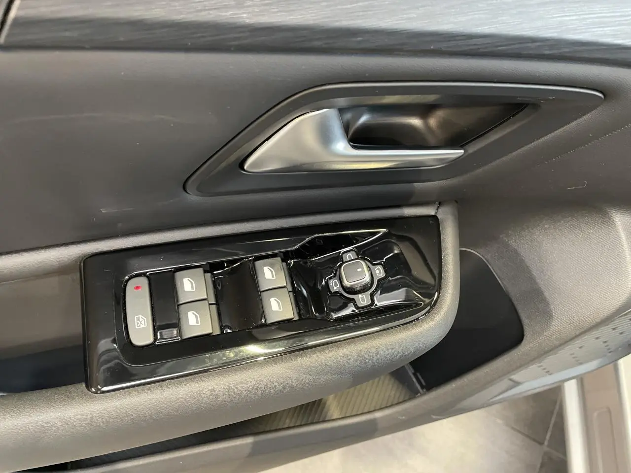 Gros plan sur la commande des vitres et rétroviseurs côté conducteur du Citroën C5 X 2024, intérieur gris foncé.