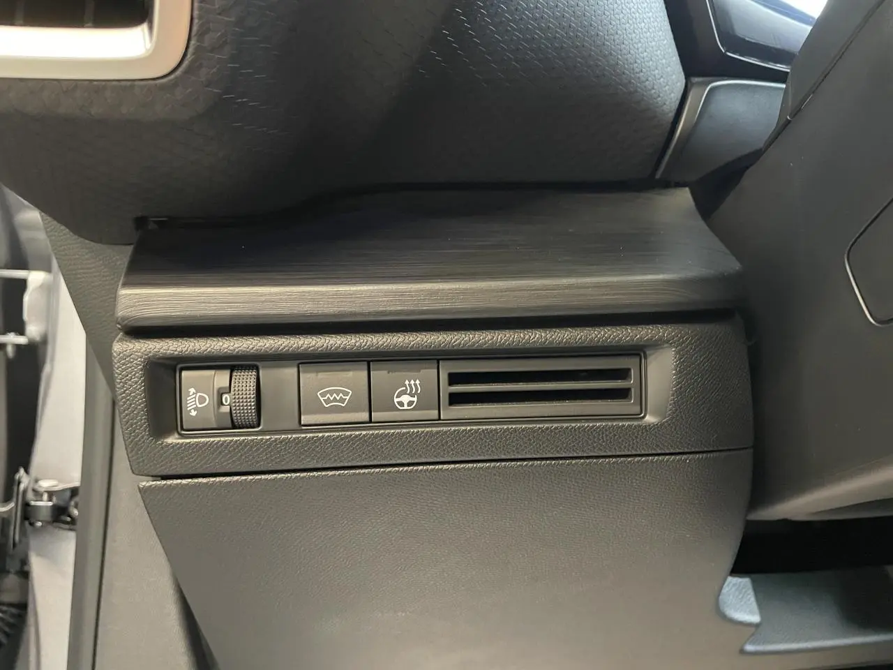 Détail intérieur du tableau de bord côté gauche de la Citroën C5 X 2024 gris foncé avec commandes et sortie d’air.
