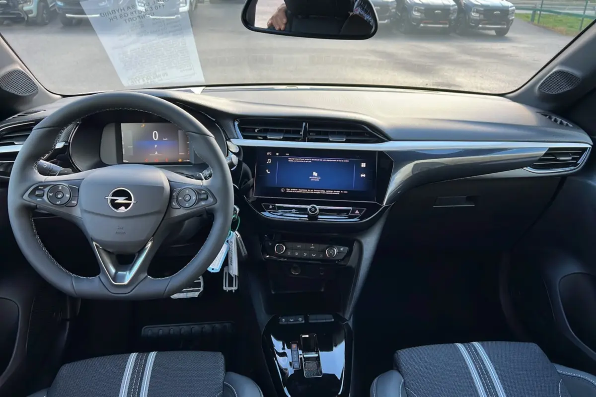 Vue intérieure frontale du poste de conduite de l’Opel Corsa Hybrid gris kristall avec écran tactile 10 pouces et volant multifonctions cuir.