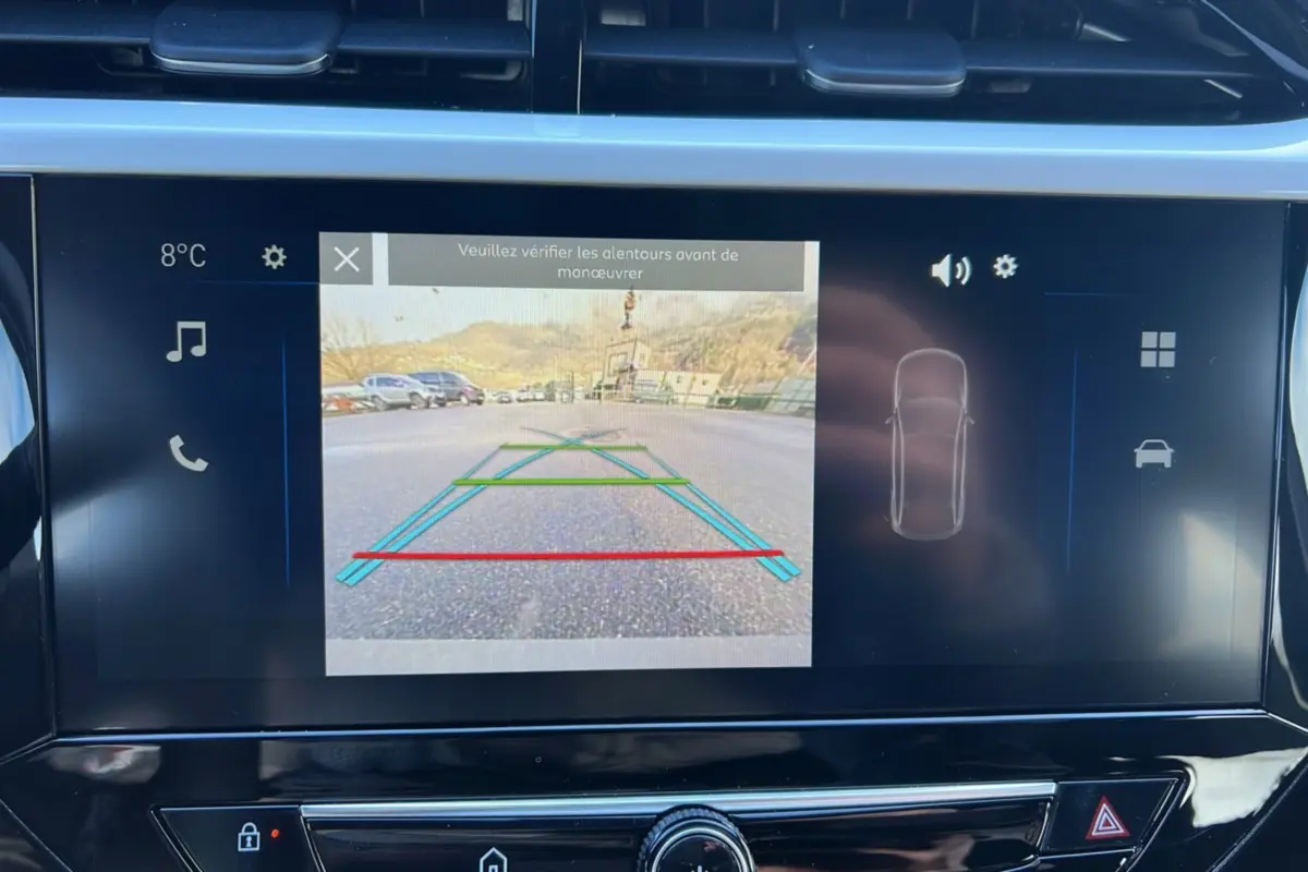 Écran tactile de la caméra de recul de l’Opel Corsa Hybrid gris, affichant les lignes de guidage au stationnement.