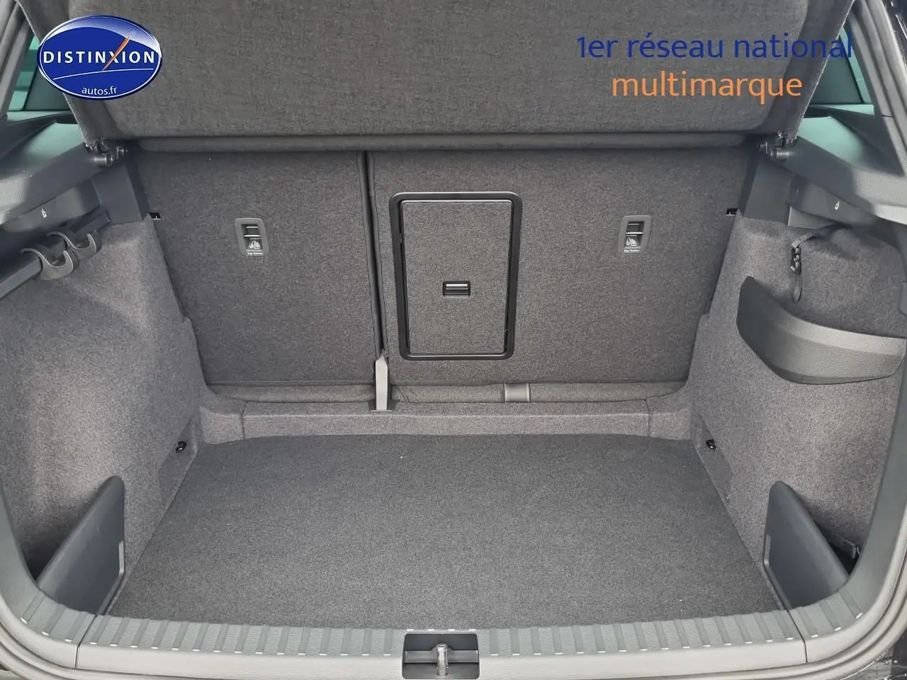 Coffre ouvert du Skoda Karoq noir 2025, montrant l'espace de chargement avec trappe à skis intégrée au dossier arrière.