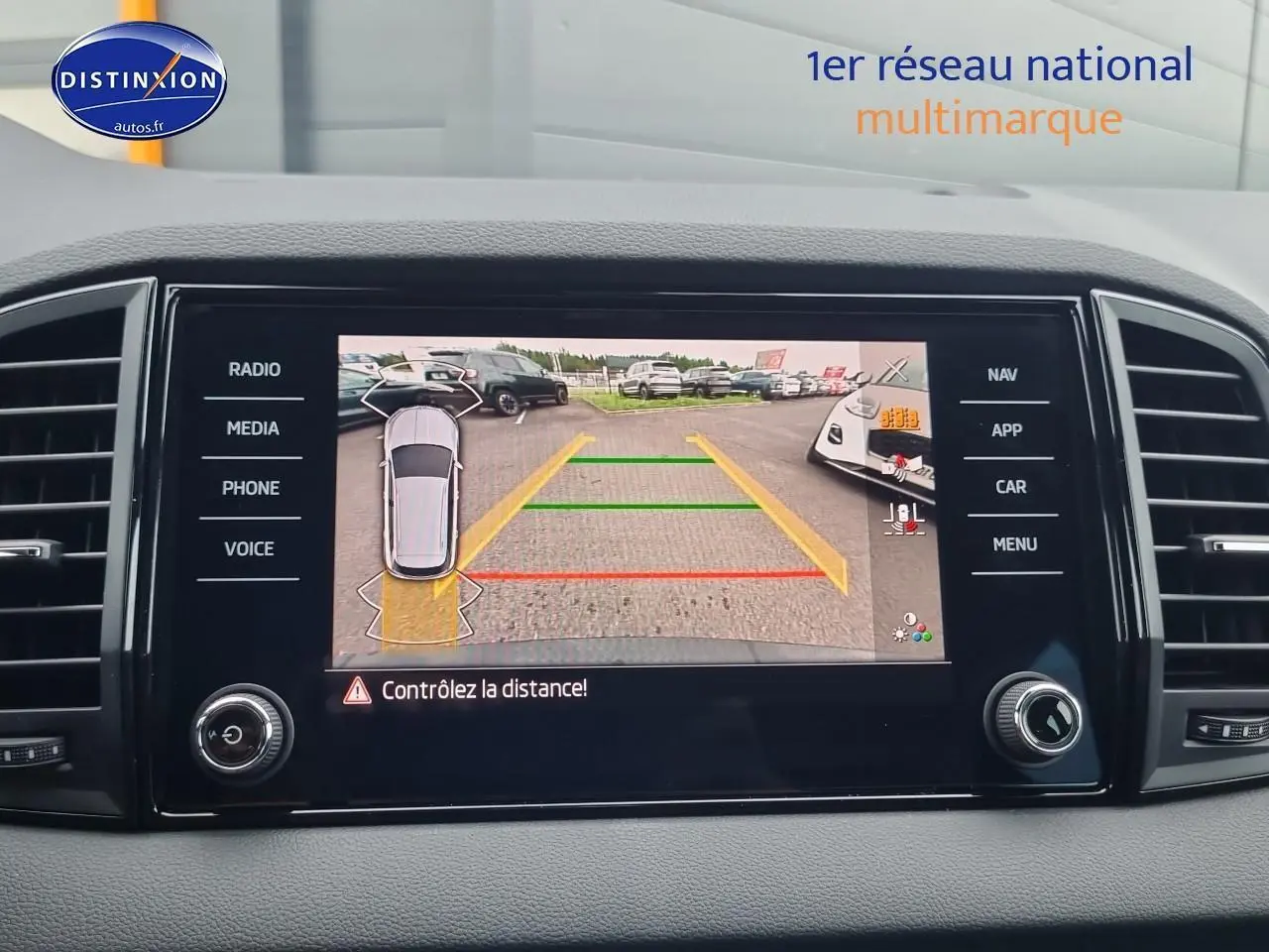 Écran tactile intérieur du Skoda Karoq noir 2025 montrant la caméra de recul avec lignes de guidage colorées.