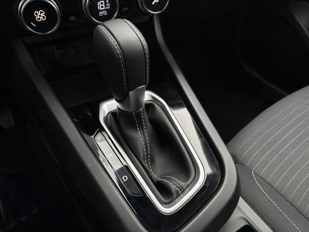 Le levier de vitesse automatique noir avec coutures blanches de la Renault Arkana TCE 140, vue rapprochée côté passager.