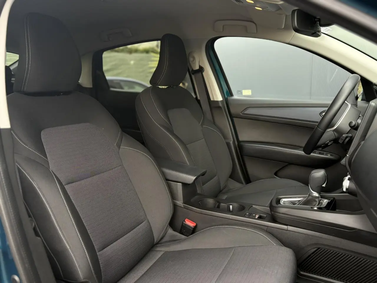 Vue intérieure côté droit du Renault Arkana 2025, sièges tissu noir avec accoudoir central et levier de boîte automatique.