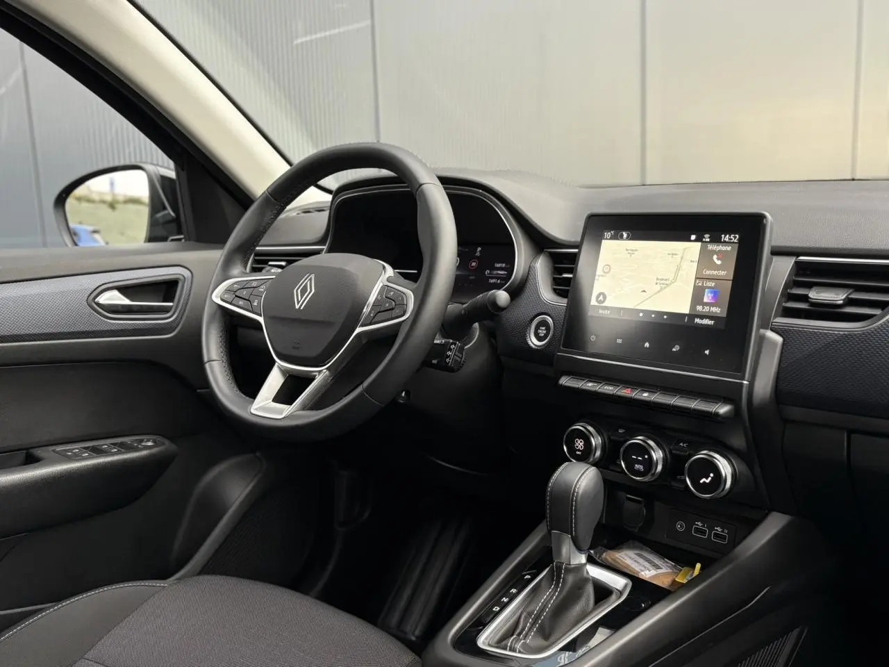 Vue intérieure côté conducteur de la Renault Arkana TCE 140 avec tableau de bord numérique et écran tactile GPS.