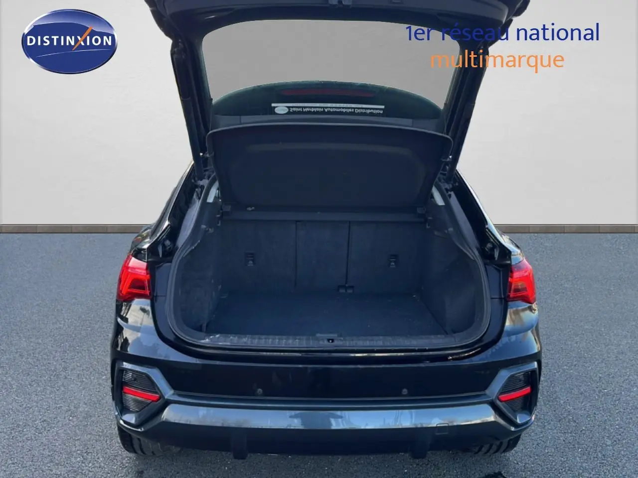 Vue arrière d’un Audi Q3 Sportback noir 2022 avec coffre ouvert montrant l’espace de chargement vide.