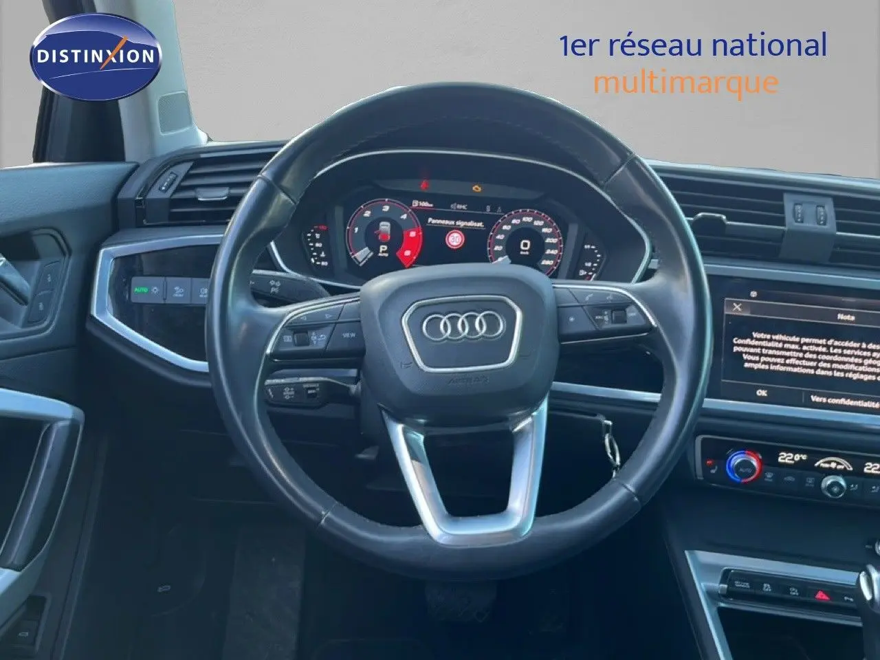 Vue intérieure centrée sur le volant et le tableau de bord numérique d’un Audi Q3 Sportback noir de 2022.