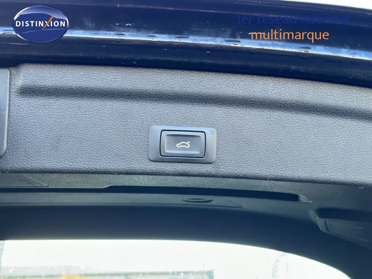 Bouton d'ouverture électrique du coffre sur la partie intérieure du hayon arrière d'un Audi Q3 Sportback noir, vue rapprochée.