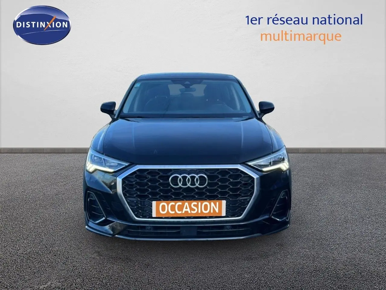 Vue de face d'un Audi Q3 Sportback noir 2022 avec calandre hexagonale et phares LED allumés.