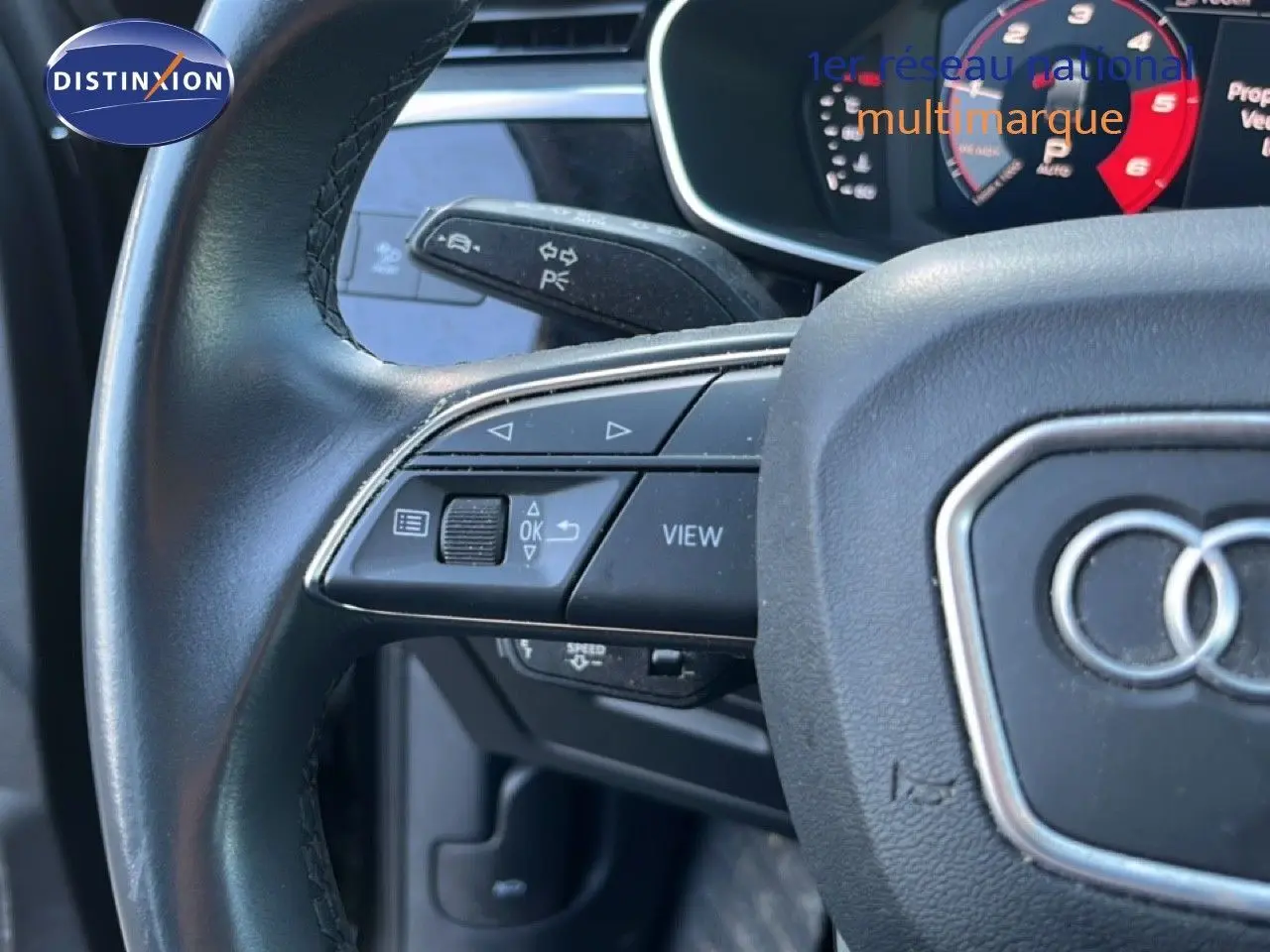 Gros plan sur le volant noir de l'Audi Q3 Sportback 35 TDI 150 S-Line avec commandes intégrées et logo Audi visible.