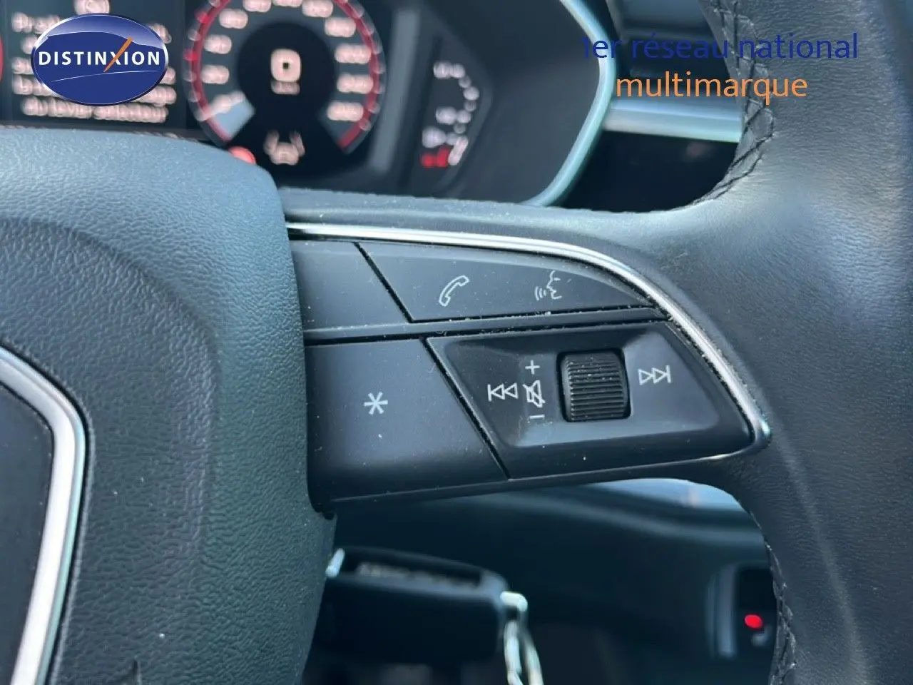 Gros plan sur les commandes au volant côté droit de l'Audi Q3 Sportback noir 2022, avec tableau de bord flou en arrière-plan.