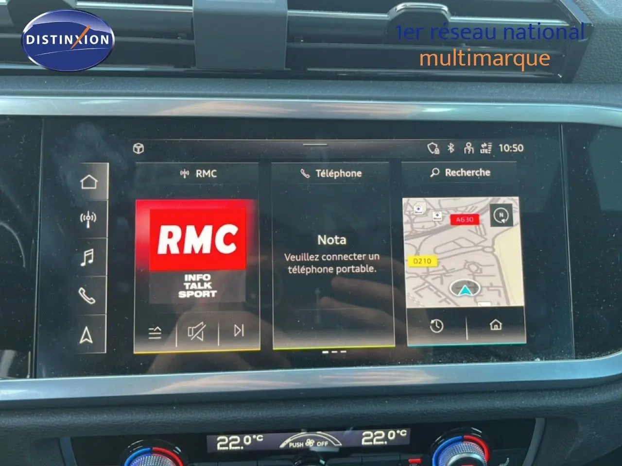 Vue rapprochée de l’écran tactile noir de l’Audi Q3 Sportback 2022 affichant la radio RMC et la navigation.